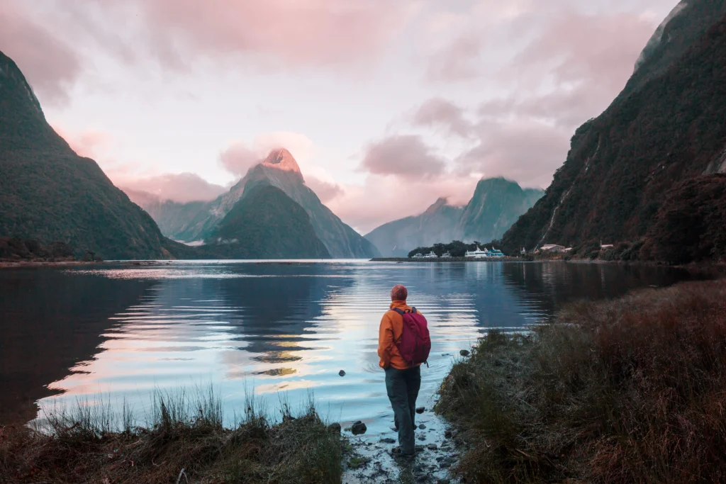 Clear waters against Milford Sound fiord in New Zealand at twilight with tourist watching the view