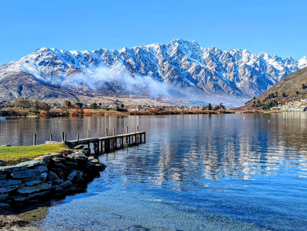 Pier and clear lake with snowy mountain in the background in Queenstown, New Zealand