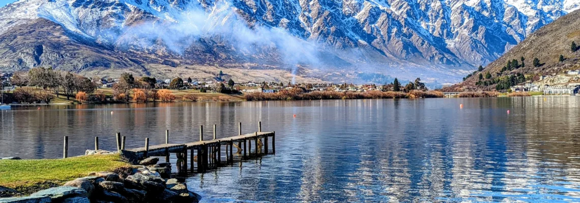 Pier and clear lake with snowy mountain in the background in Queenstown, New Zealand