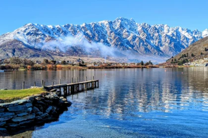 Pier and clear lake with snowy mountain in the background in Queenstown, New Zealand
