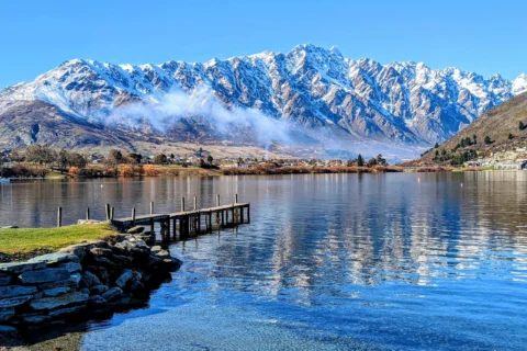 Pier and clear lake with snowy mountain in the background in Queenstown, New Zealand