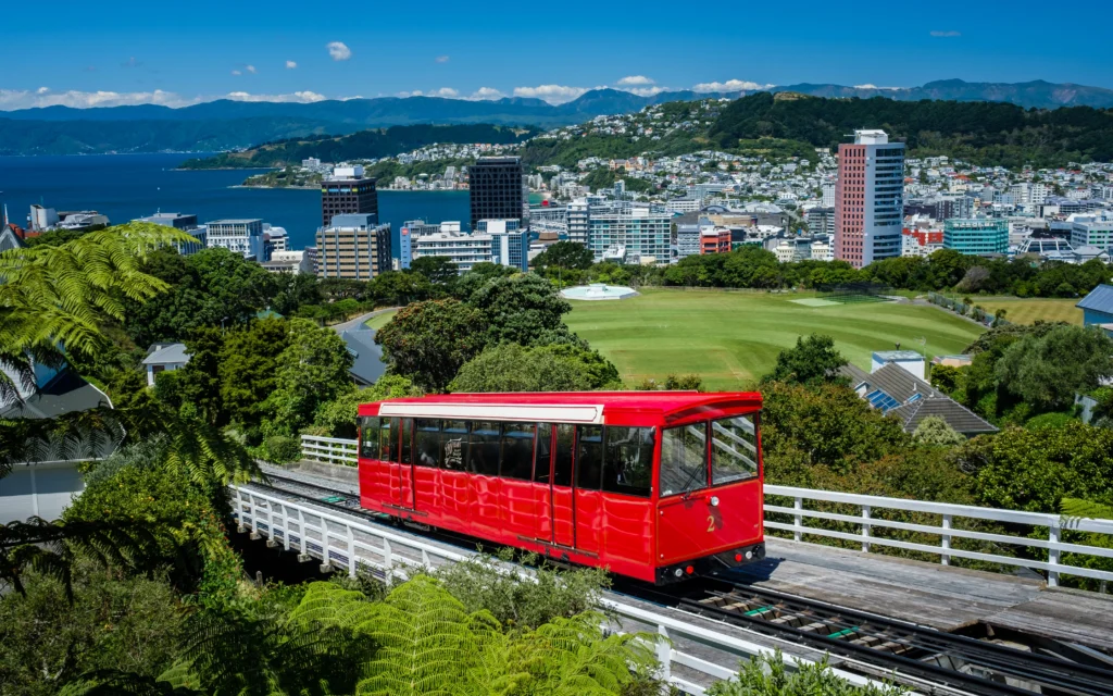 Red Wellington rail car in foreground, with Wellington CBD in the background