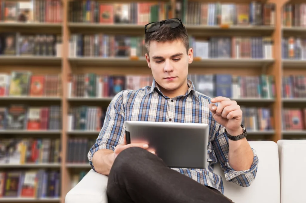 Man on his iPad sitting in a library researching