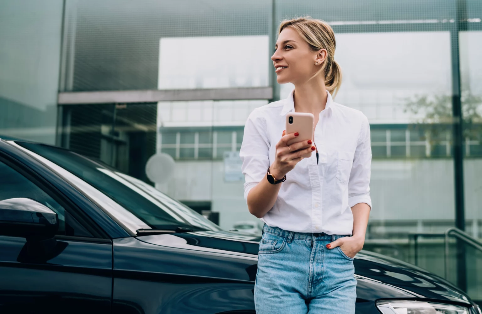 Women happy standing next to her shiny fixed car with her phone after getting a quick car repair loan