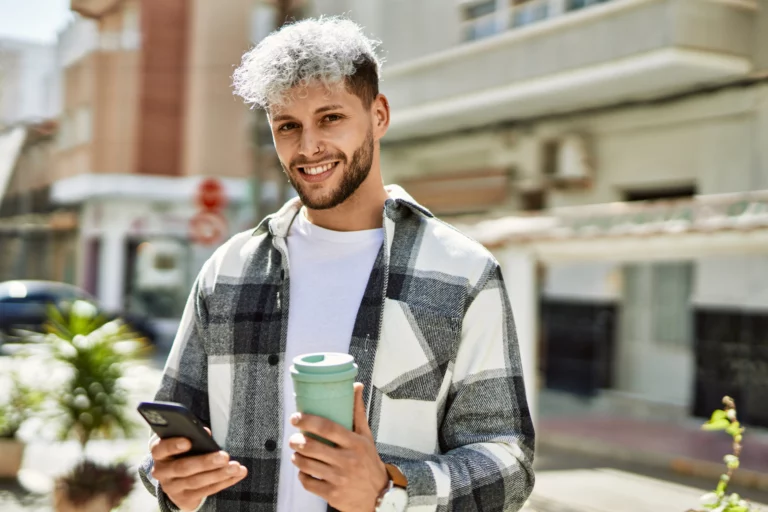 man smiling outside as he applies for a small personal loan on his phone