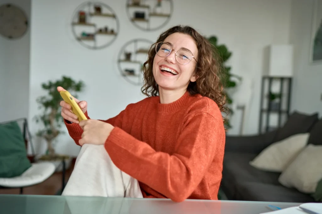 woman holding her phone smiling because she learned how to make money online in NZ